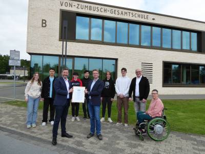 Brgermeister Marco Diethelm bergibt die Fairtrade-Town Urkunde an Sebastian Menke, dem Leiter der von-Zumbusch-Gesamtschule in Anwesenheit von Schlerinnen und Schler der Fairtrade-Gruppe, Fachbereichsleiter Wilhelm Towara aus dem Rathaus sowie der didaktischen Leiterin an der Schule, Anne Fallner-Ahrens.